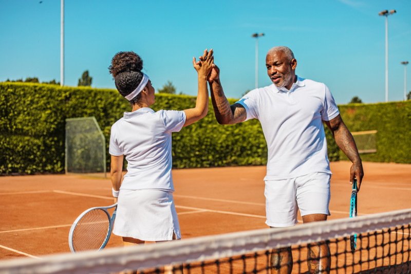 Dad and Daughter Playing Tennis Inside the Woodfield Country Club Real Estate